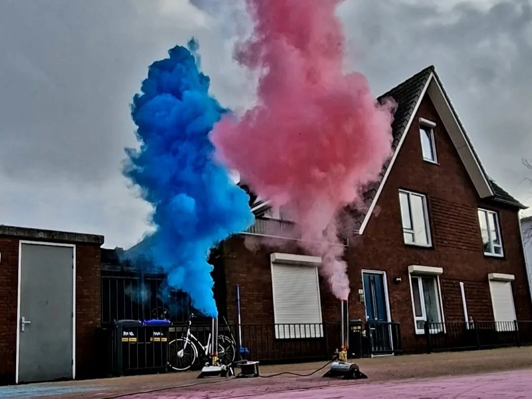 Onze eigen poederkanonnen schieten op straat tegelijk een blauwe en een roze poederwolk de lucht in